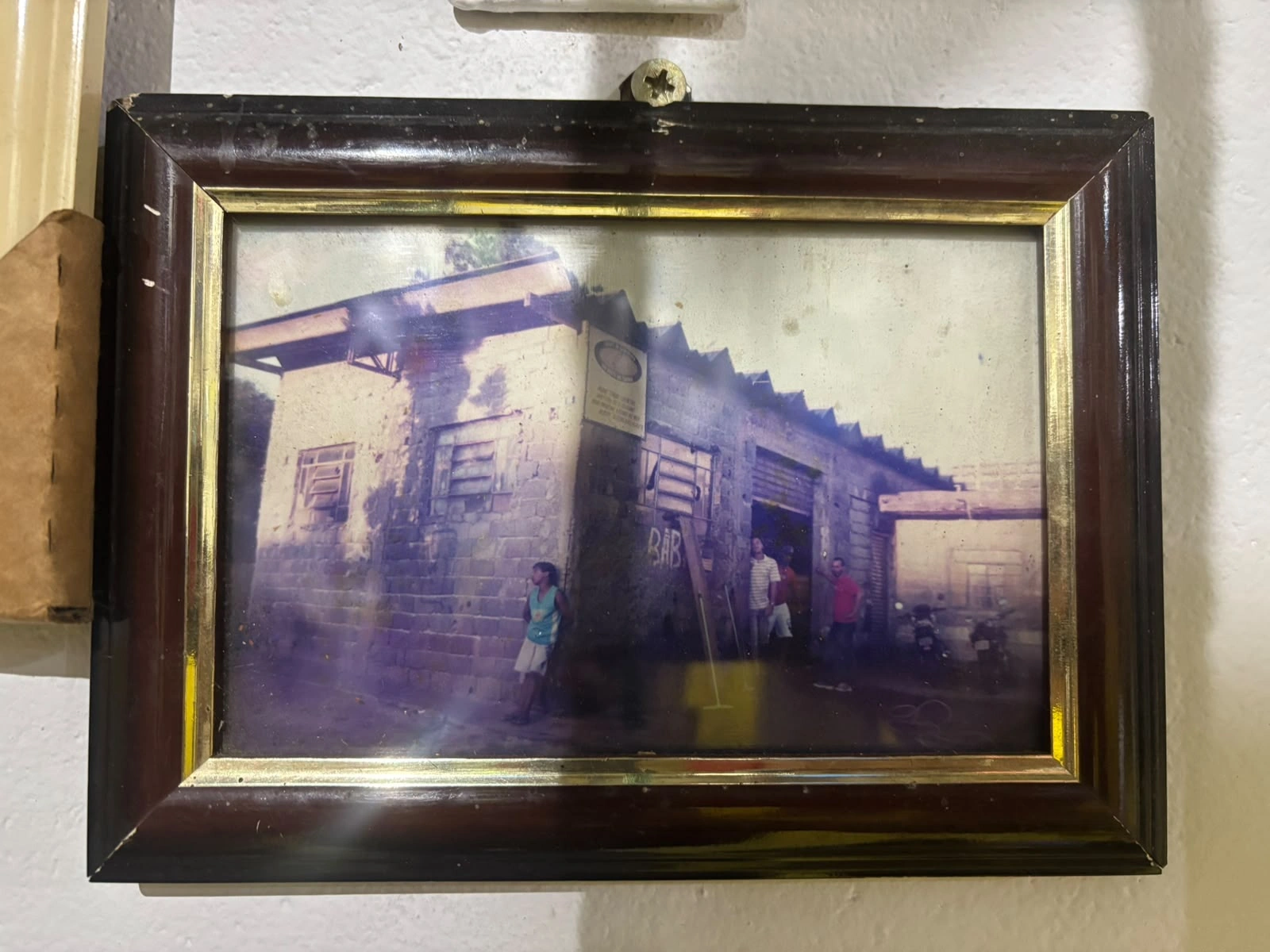 Foto antiga emoldurada da fachada da matriz, ainda de blocos sem pintura, com pessoas na porta