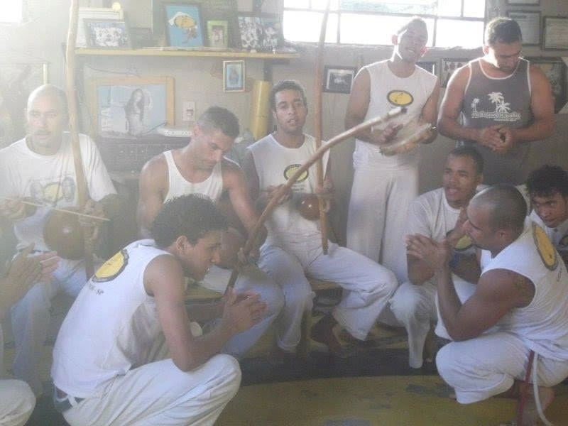 Capoeiristas tocando berimbau e pandeiro e cantando na roda da matriz